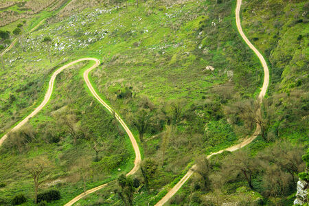 Aerial view to the side road through the green grass field