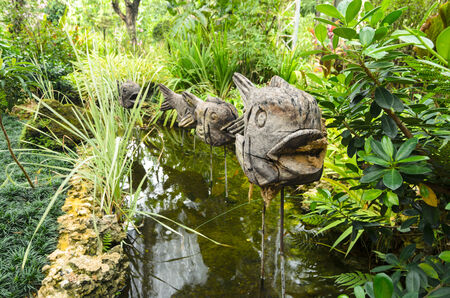 Wooden fish on a stick as a decoration in a chanel in the park among tropical green plantsの写真素材
