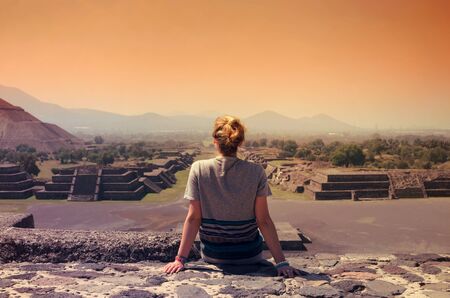 Young woman sitting at the edge of ancient pyramid at Teotihuacanの写真素材