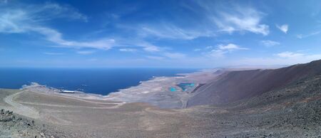 Aerial view to the desert meeting with the ocean, little port and industrial side with colorful artificial lakesの写真素材
