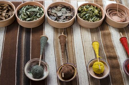 Colorful threds on wooden spindles and bowls with natural colorants