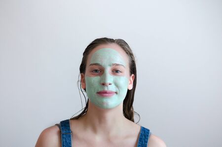 Portrait of a young woman with green creamy facial mask on her faceの写真素材