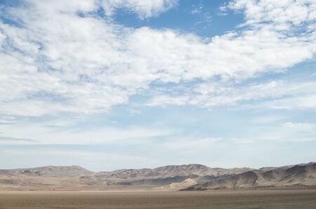 Arid lands of the desert under blue cloudy skyの写真素材