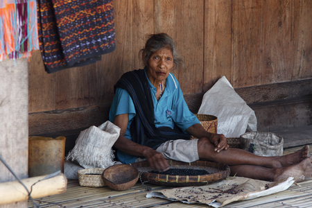 BENA, FLORES ISLAND, INDONESIA, 17 APRIL 2012: old indigenous woman sorts out beans on the porch of her rustic houseのeditorial素材