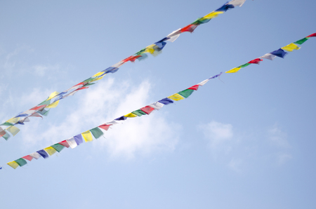 Strings of colorful Buddhist Prayer flags on the wind agains blue sky