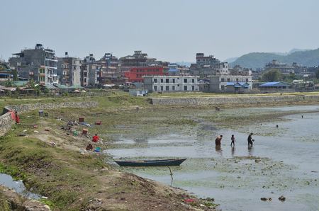 POKHARA, NEPAL, 2013-04-02: local people doing their laundry  and fishing at the shore of the lakeのeditorial素材