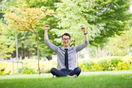 Young asian & success businessman using tablet, laptop, mobile phone in the parkの写真素材