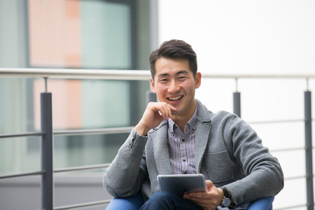 Young asian businessman using tablet, mobile phone in the officeの写真素材
