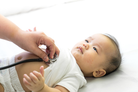 Doctor exams Asian newborn baby with stethoscope in the hospitalの写真素材