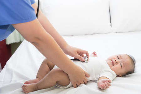 Doctor exams Asian newborn baby with stethoscope in the hospitalの写真素材