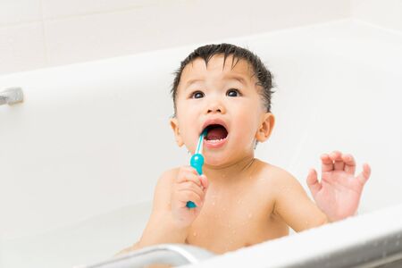 Asian baby uses toothbrush in the bathroomの写真素材