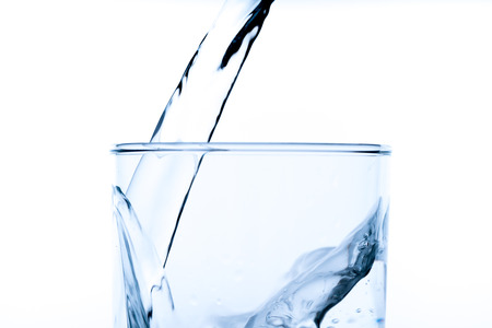Glass of water with pouring from the bottle, studio shot