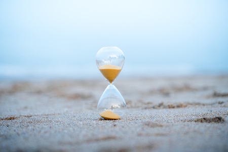 Sand clock on the beach, business time management concept