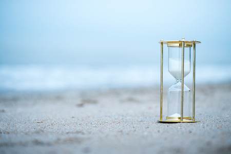 Sand clock on the beach, business time management concept