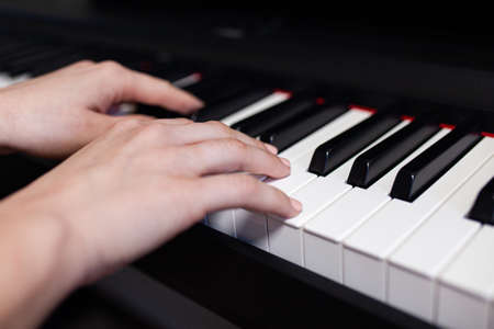 Woman hand's playing on the piano close up detail