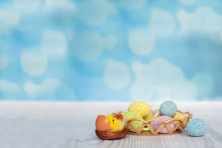 Toy funny chiken near easter eggs on colored background