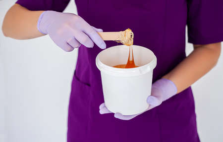Natural honey sugar paste shugaring closeup. Women beautician holds jar wax of paste for sugar...