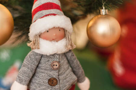macro detail of christmas doll with christmas decorations background and christmas lights in golden green and red tonesの写真素材