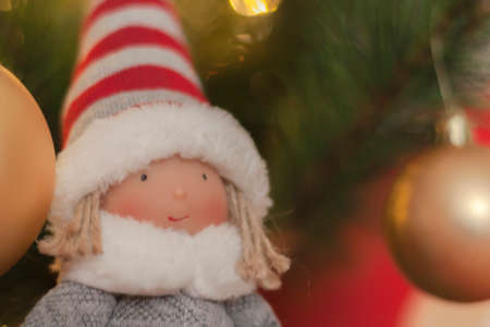 macro detail of christmas doll with christmas decorations background and christmas lights in golden...