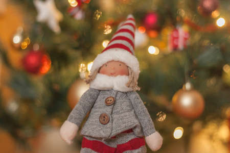 macro detail of christmas doll with christmas decorations background and christmas lights in golden...