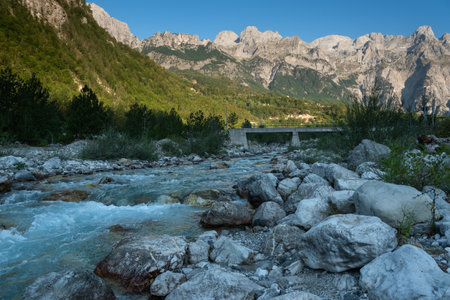 Mountain landscape with a river and a bridge in the foreground.の写真素材