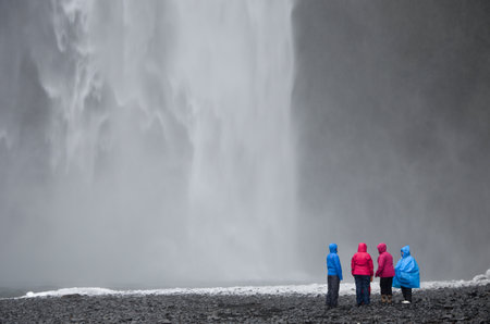 Group of people standing in front of Skogafoss waterfall, Icelandの写真素材