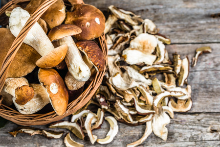 Fresh boletus mushrooms in a basket and dry mushrooms on wooden table, overheadの写真素材