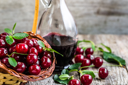 Cherry wine in a rustic bottle, homemade alcohol tincture on wooden tableの写真素材