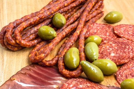 Assortment of meats: kabanos, salami prosciutto slices on wooden board.の写真素材