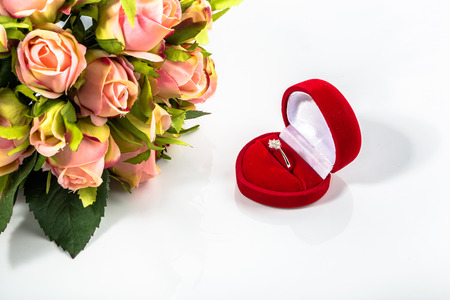 Engagement ring and bouquet of roses on a white background.の写真素材