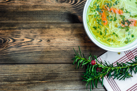 Chicken broth soup with noodles on a wooden table.の写真素材
