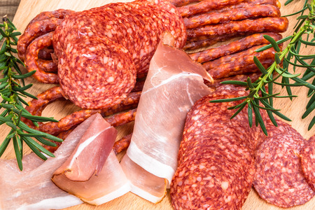 Assortment of meats: kabanos, salami prosciutto slices on wooden board.の写真素材