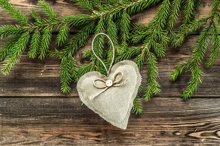 Textile decorative pillows in shape heart hanging on christmas tree branchの写真素材