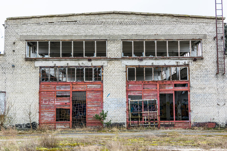 Abandoned industry, old industrial factory wall of white bricks with damaged door and windowsの写真素材