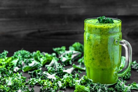 Jar of smoothie with green vegetables, leaves of kale in a glass on black backgroundの写真素材