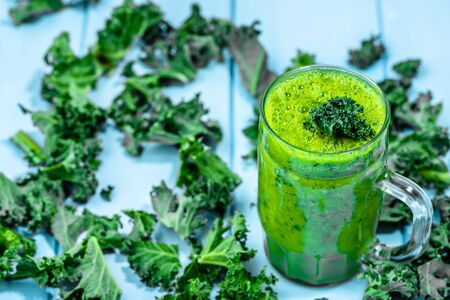 Green vegetable smoothie with blended leaves in jar mug on blue backgroundの写真素材