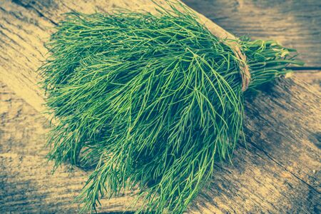 Fresh dill bunch on rustic background, the concept of herbs used for healthy cooking in vegetarian cuisineの写真素材