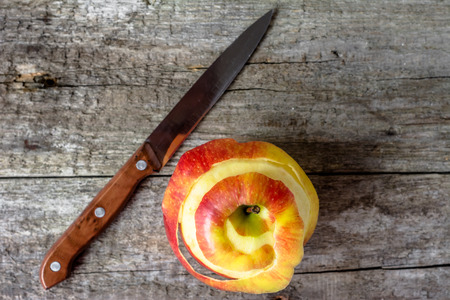 One apple with peeled peel on wooden table from aboveの写真素材