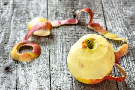 One apple with peeled peel on wooden tableの写真素材