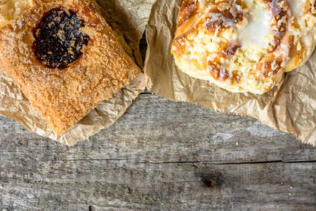Unhealthy food breakfast - french pastry and sweet bun on wooden table, copy space, flat lay from aboveの写真素材