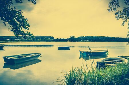 Landscape stylized on vintage with boats for fishing on the lake at the shore. Vintage photo. Nature background. Tranquil landscape.の写真素材