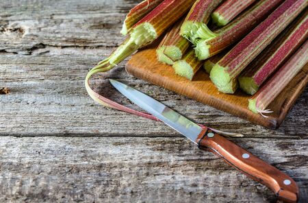 Fresh rhubarb stalks on wooden board for cuttingの写真素材