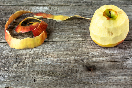 One apple with peeled peel on wooden table, copy spaceの写真素材