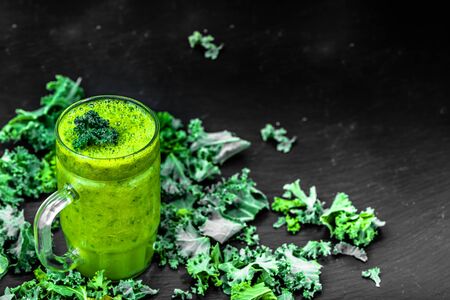 Glass of smoothie with green vegetables, leaves of kale in a jar on black backgroundの写真素材