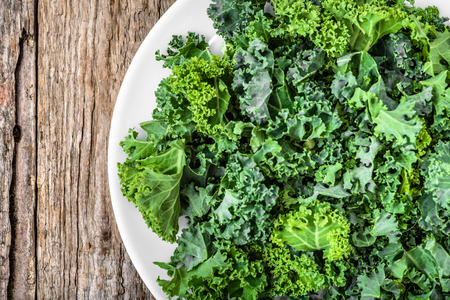 Green vegetable, leaves of kale, overhead view, closeup on white plateの写真素材