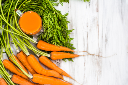 Healthy smoothie from carrots in glass and fresh carrots on white backgroundの写真素材