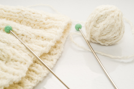 Skein of wool and knitting needle isolated on white background