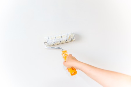 Hand painting wall using paint brush, working indoors, home renovation conceptの写真素材