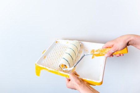 Painting wall using paint roller, working indoors, home renovation conceptの写真素材