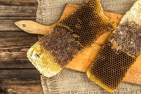 Honeycombs with honey on rustic wood background covered with jute sackcloth, top view.の写真素材
